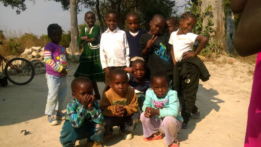 A group of children posing together outside in the community.