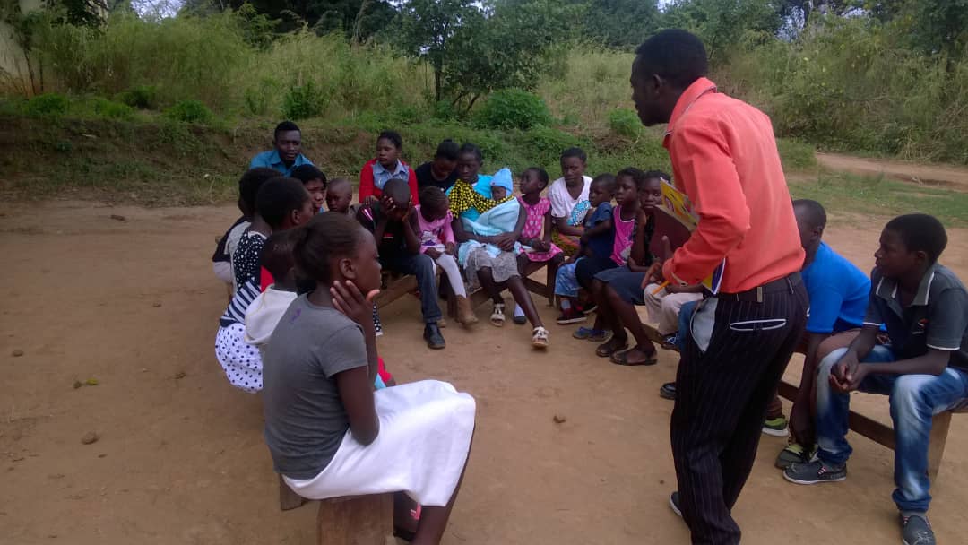 Children and community members gathered outdoors for a support and learning session.