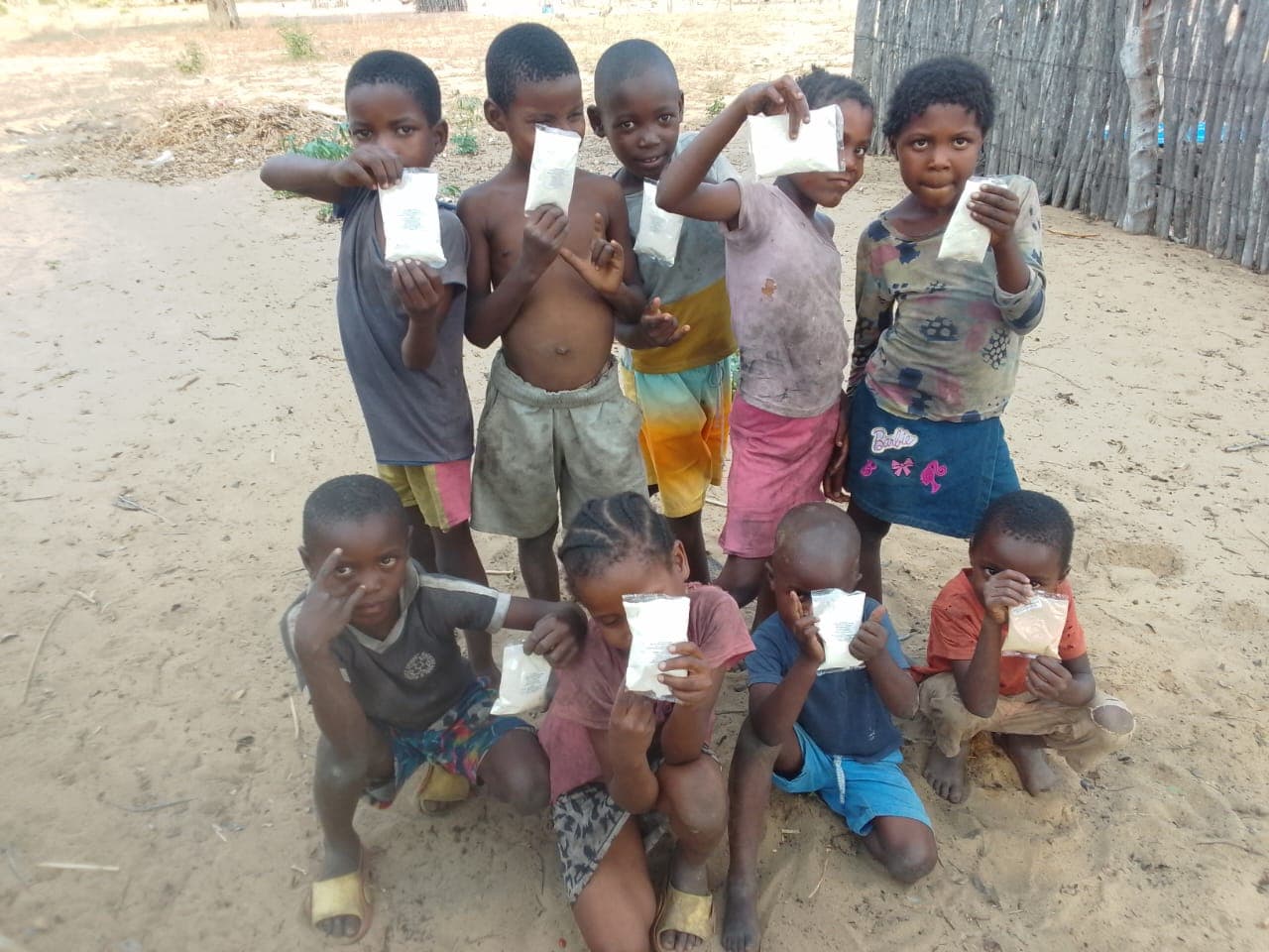 A group of children outdoors holding individual food packets.