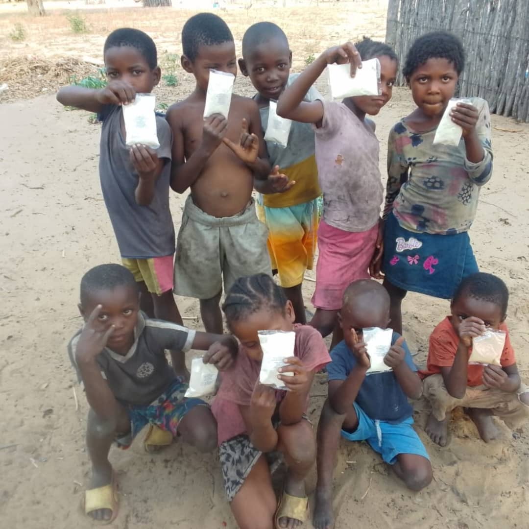 Children posing together outdoors with the food packets they received.