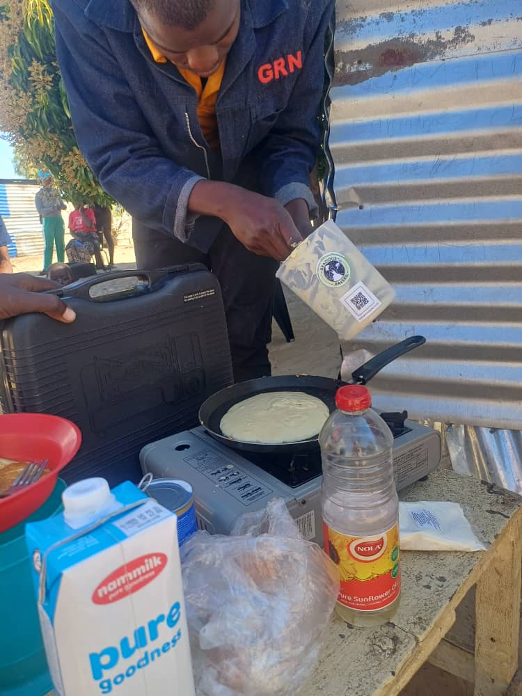 A community member preparing food on a portable stove outdoors.
